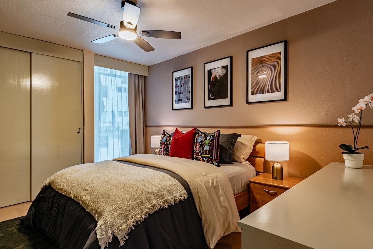 Bedroom 1 features a king-size bed, a ceiling fan, closet space, and colorful accent pillows.