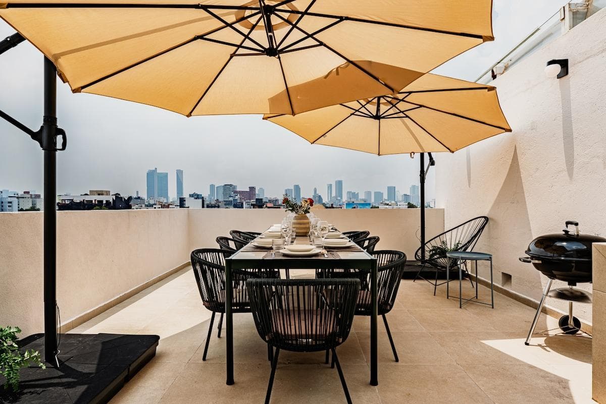 Spacious private terrace with an outdoor dining table, barbecue grill, and skyline backdrop.