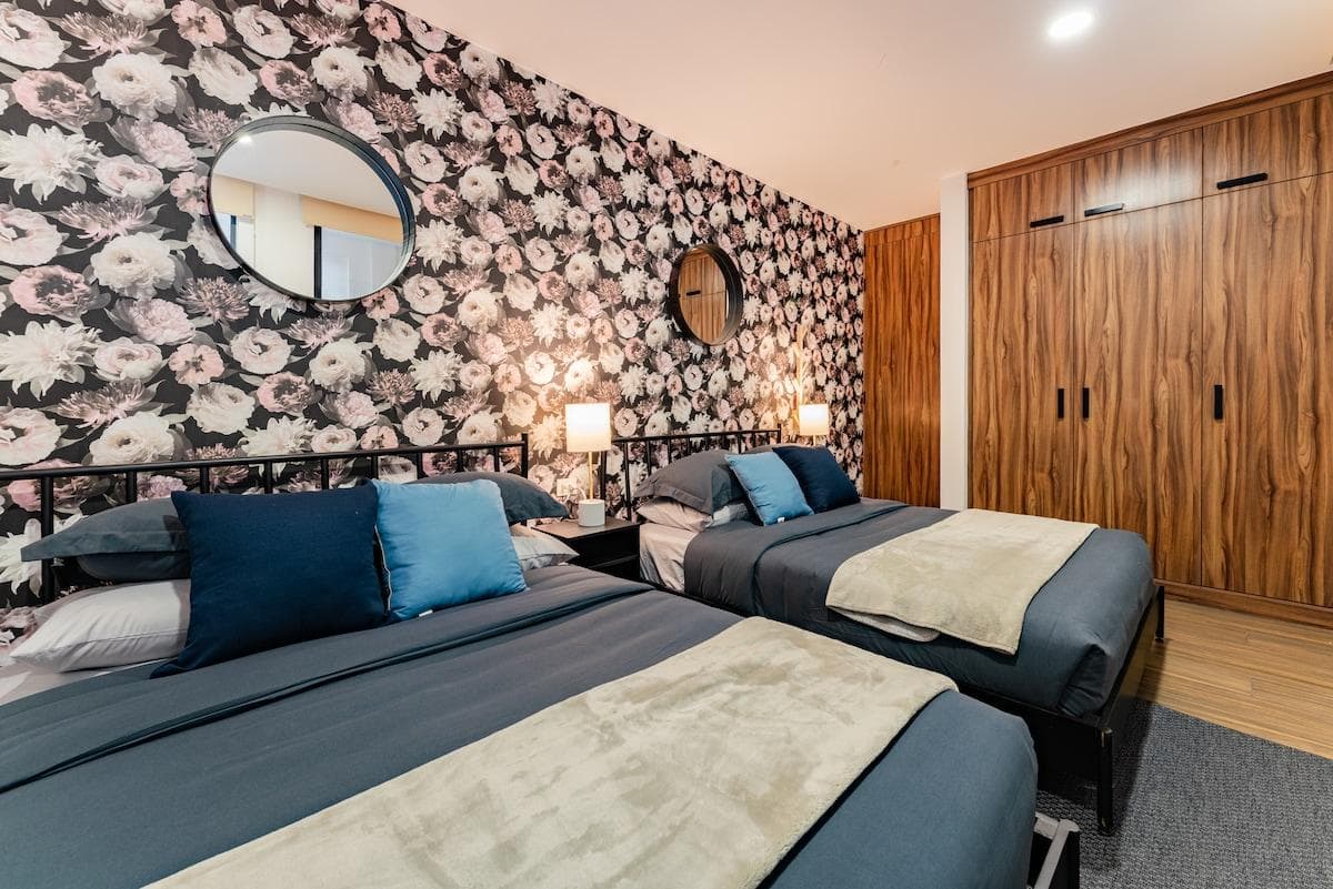Unique bedroom with two double beds, stylish floral wall, and soft lighting