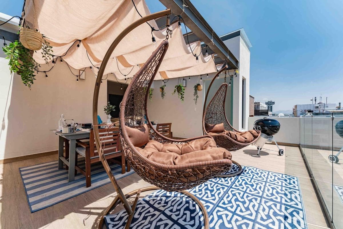 Rooftop seating area with hanging chairs and urban views.