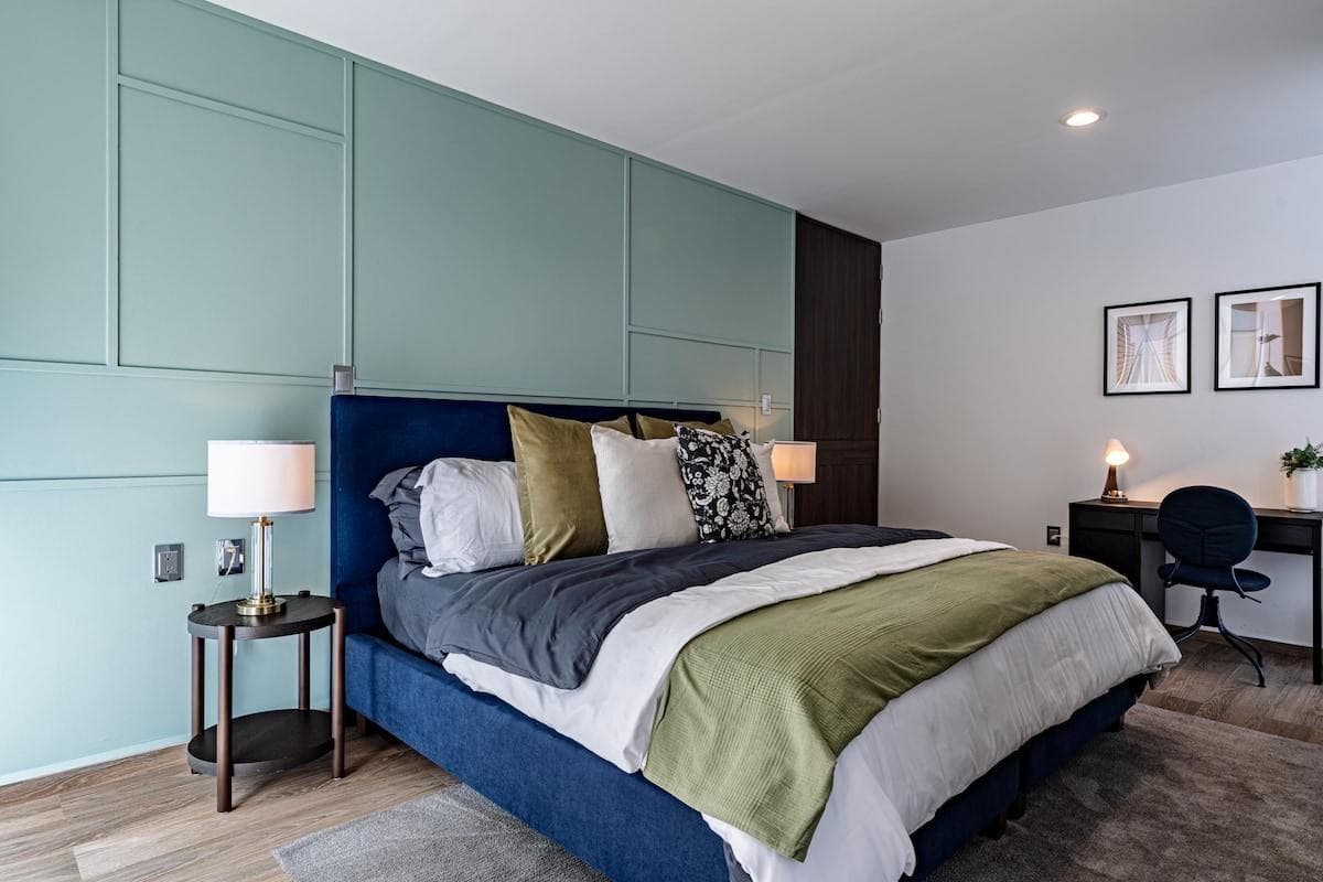 Muted green accents and layered textures create a soothing bedroom ambiance