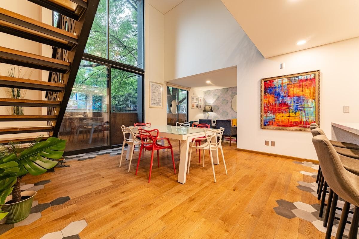 Bright dining area with bold artwork and double-height windows.