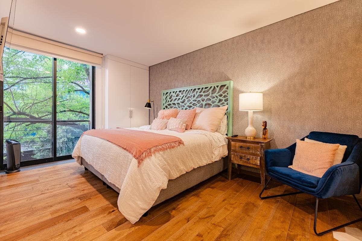 Inviting bedroom with king bed, cozy armchair, and soft lighting.