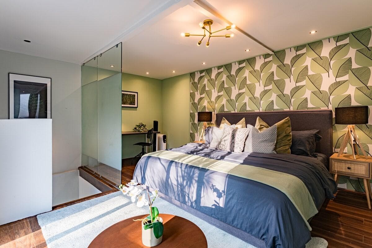 Bedroom with luxurious bedding, vibrant accents, and soothing green tones.